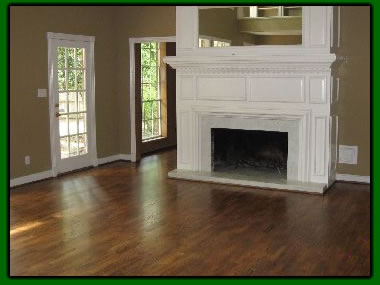 Refinished hardwood floor glowing in a Houston living room with a white fireplace