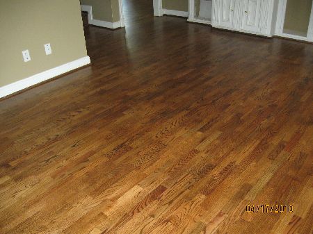 Medium-brown short-length oak strip wood flooring glued down across a Houston living room
