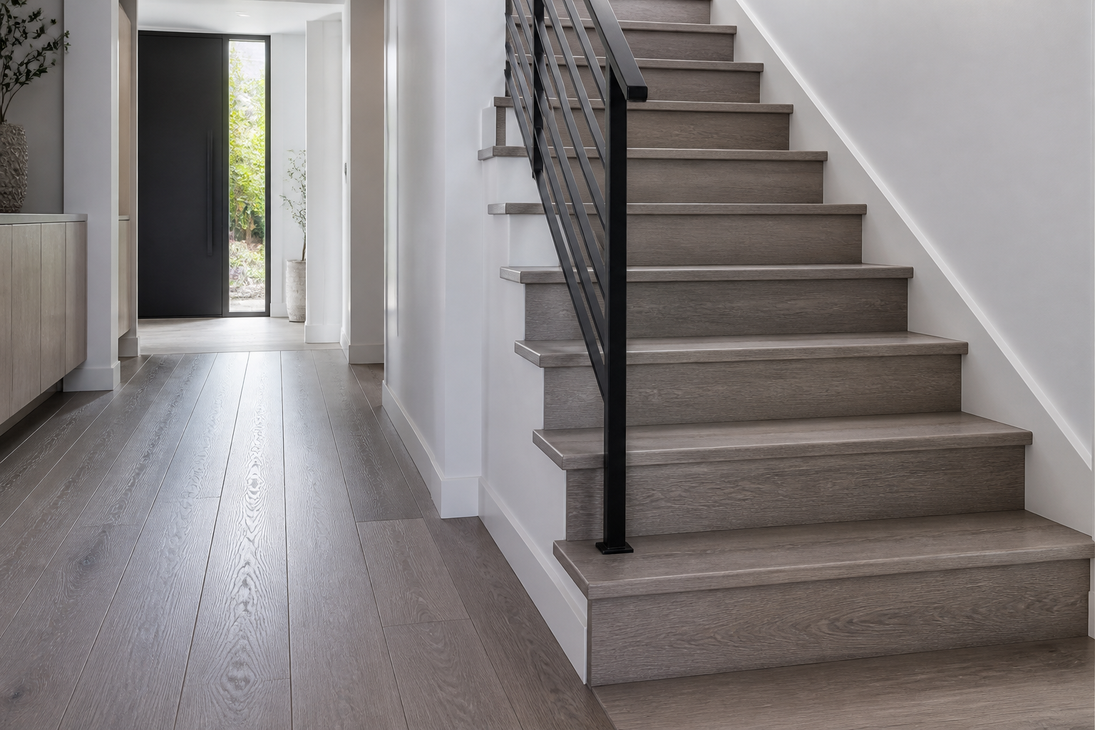 Modern gray hardwood stair treads with a black metal railing and matching entry floor