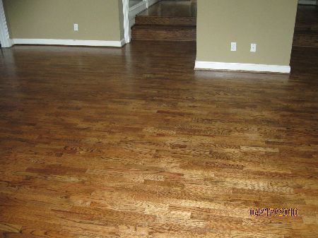 Quartersawn white oak hardwood floor with amber ray-fleck grain near a stone fireplace in a Houston-area home